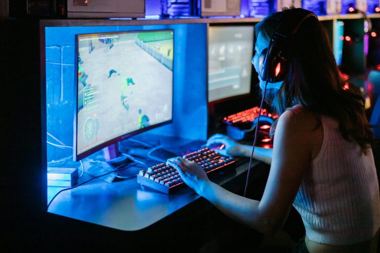 Woman enjoying a vibrant gaming session at a computer setup with a mechanical keyboard.