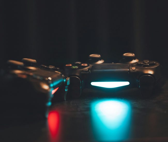 Close-up of glowing gaming controllers on a dark surface, creating a moody ambiance.