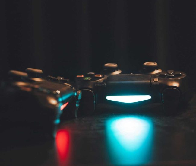 Close-up of glowing gaming controllers on a dark surface, creating a moody ambiance.