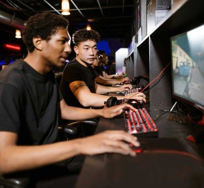 Group of young adults enjoying a competitive gaming session on computers indoors.