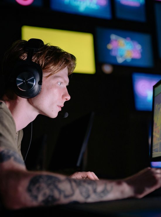 Engaged gamer wearing headphones intensely playing on a computer monitor indoors.