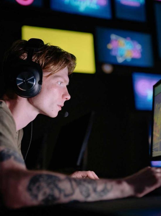 Engaged gamer wearing headphones intensely playing on a computer monitor indoors.